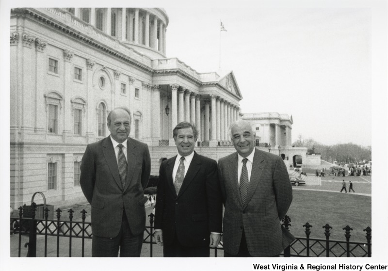 Representative Nick J. Rahall (D-W.Va.) stands between two unidentified men outside the United States Capitol building.