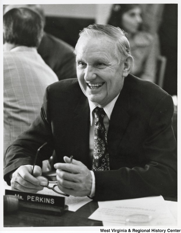 Congressman Carl Perkins (D-KY) smiling at a table.