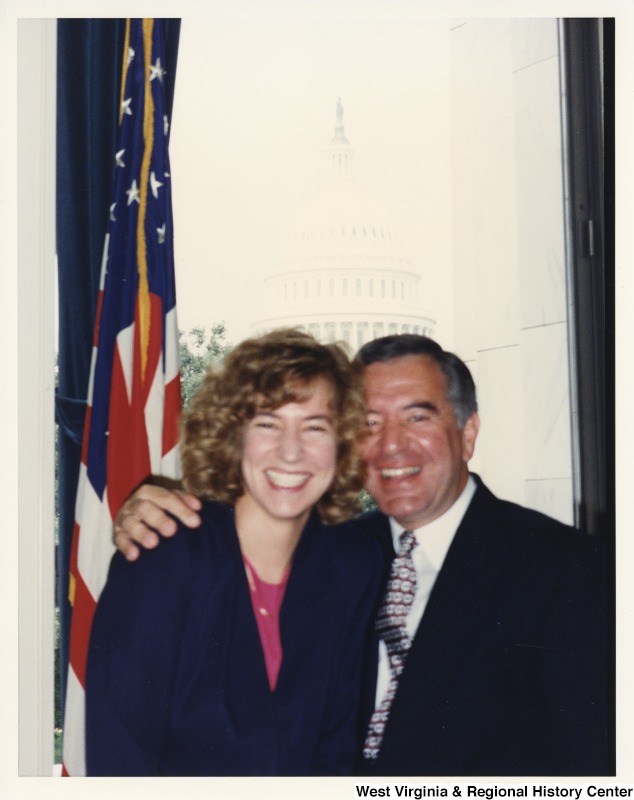 On the right, Representative Nick J. Rahall (D-W.Va.) smiles for a photograph with a female staff member. The United States Capitol building can be seen in the background.