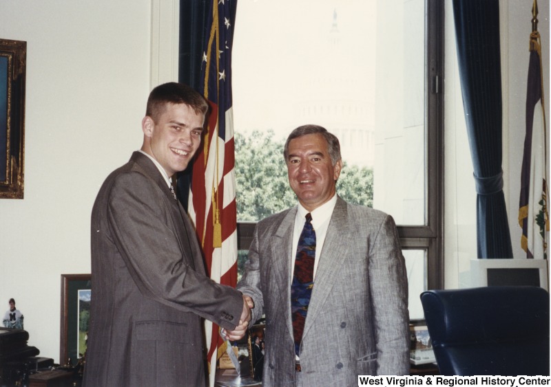 On the right, Representative Nick J. Rahall (D-W.Va.) shakes hands with an unidentified young man.