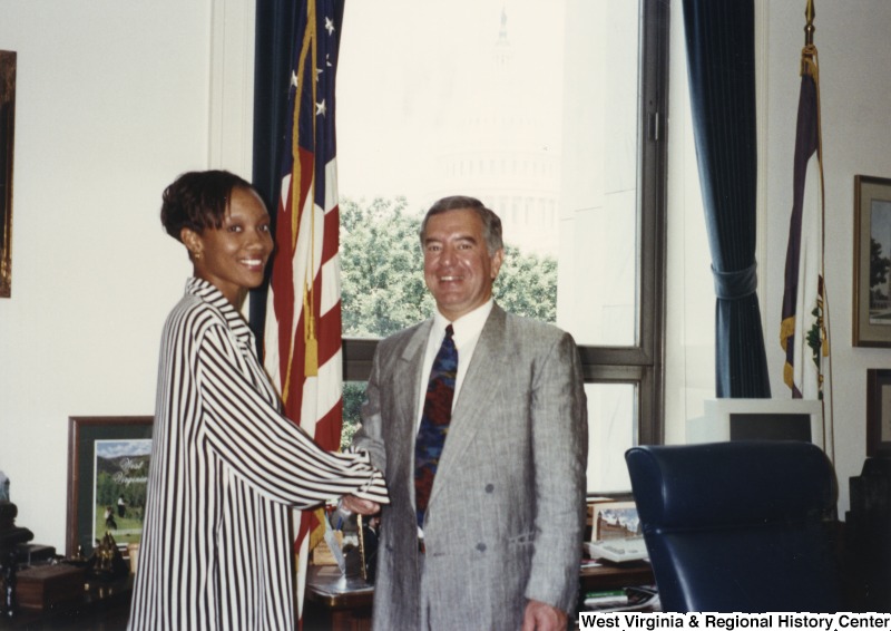 On the right, Representative Nick J. Rahall (D-W.Va.) shakes hands with an unidentified woman.