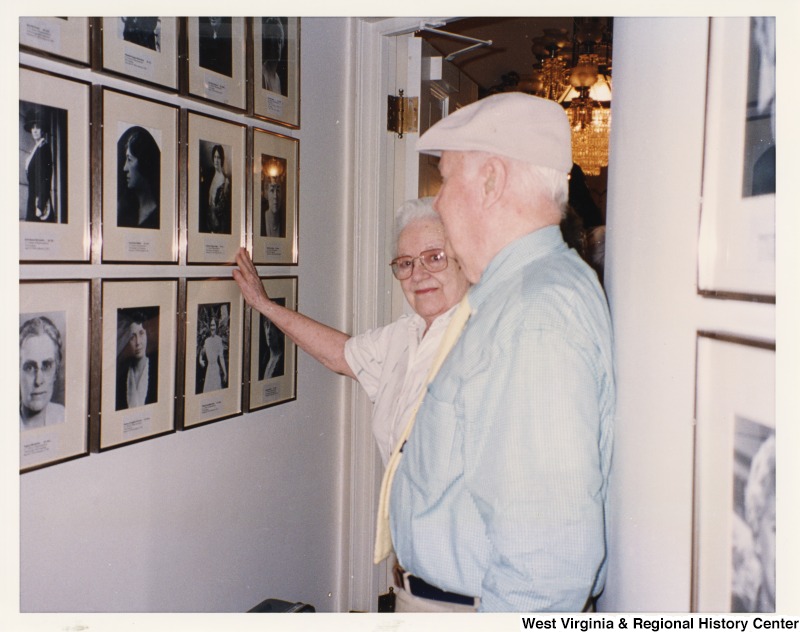 An unidentified man and woman looking at photographs on the wall. Both people are related to David Todd.