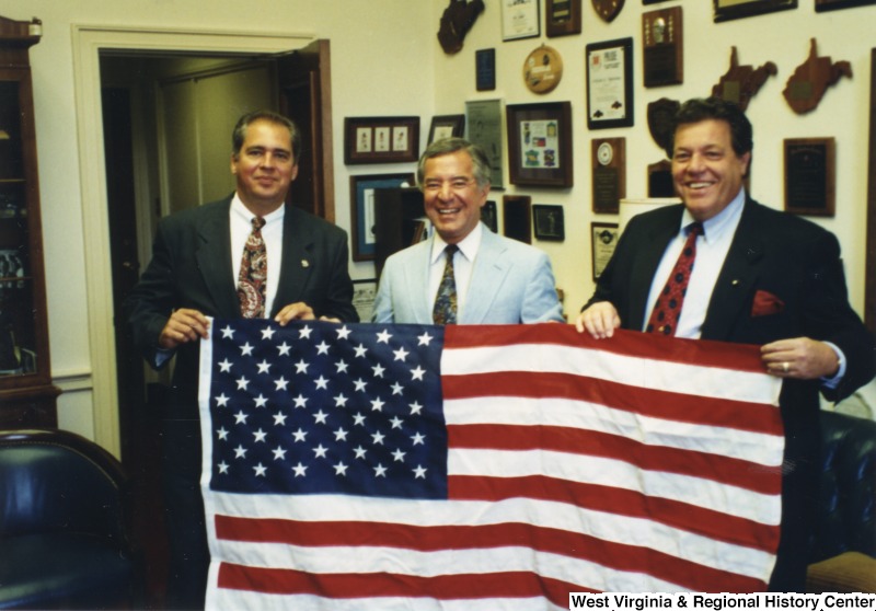 L-R: Senator Earl Ray Tomblin (D-W.Va.), Representative Nick J. Rahall (D-W.Va.), unidentified man. These three men hold an American flag.