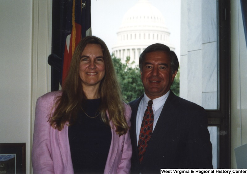 On the right, Representative Nick J. Rahall (D-W.Va.) stands for a photograph with an unidentified woman while the United States Capitol can be seen in the background.