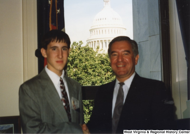 On the right, Representative Nick J. Rahall (D-W.Va.) shakes hands with an unidentified man in his office.