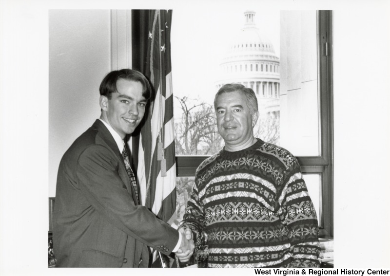 On the right, Representative Nick J. Rahall (D-W.Va.) shakes hands with an unidentified man.