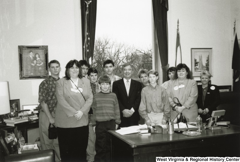 Representative Nick J. Rahall (D-W.Va.) stands behind his desk with a group of unidentified people.