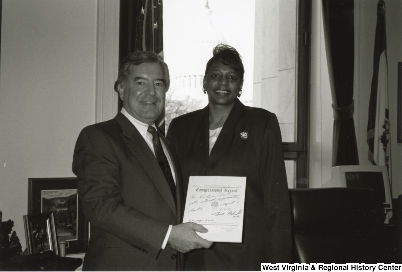 On the left, Representative Nick J. Rahall (D.W.Va.) holds a "Congressional Record" and stands for a photograph with an unidentified woman.