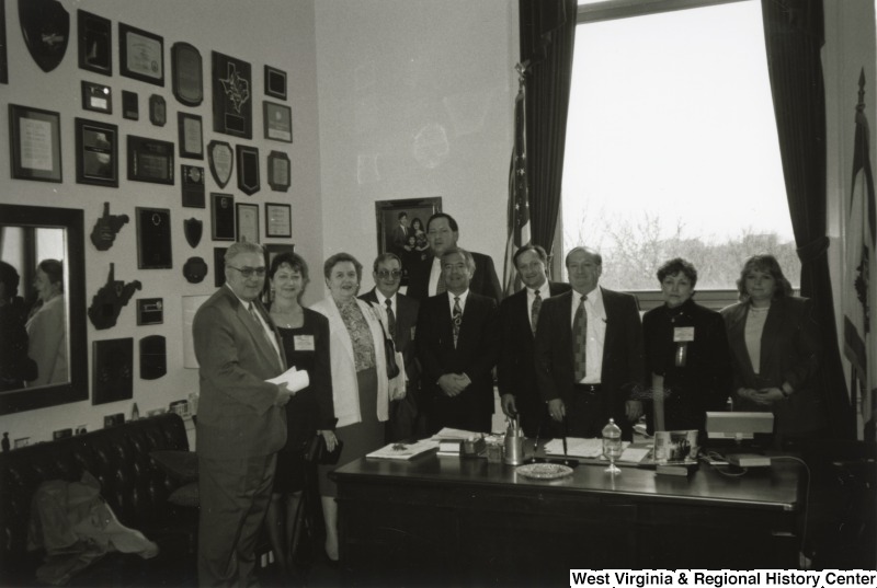In the center, Representative Nick J. Rahall (D-W.Va.) stands for a photograph in the midst of a group of nine unidentified people around a desk.