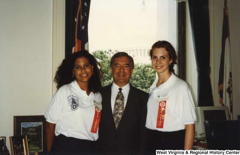 Representative Nick J. Rahall (D-W.Va.) stands between two unidentified women wearing ribbons for a photograph.
