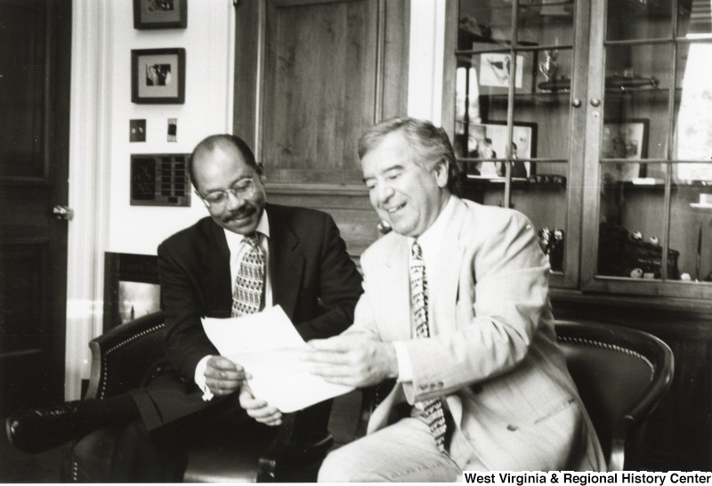On the right, Representative Nick J. Rahall (D-W.Va.) sits with an unidentified man and looks over a paper.