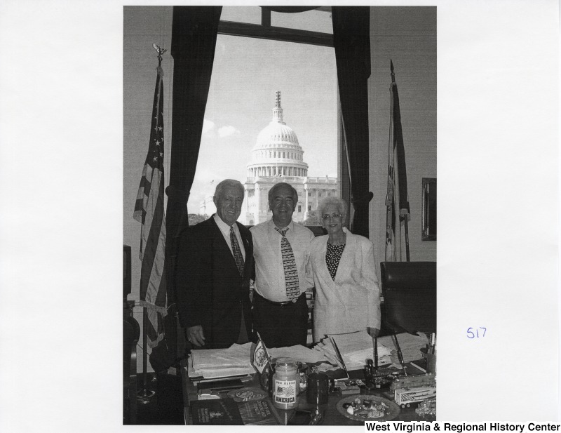Representative Nick J. Rahall (D-W.Va.) stands between an unidentified man and an unidentified woman for a photograph in his office.