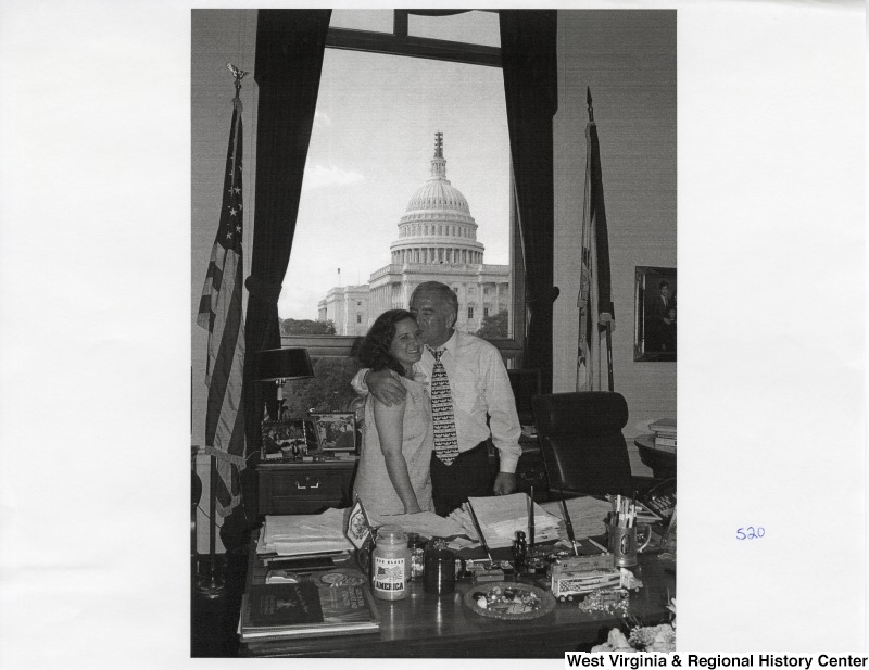 On the right, Representative Nick J. Rahahll (D-W.Va.) kisses one of his daughters on the top of the head in his office.