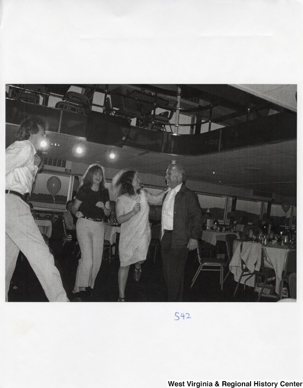 Four unidentified people dance together at a party.