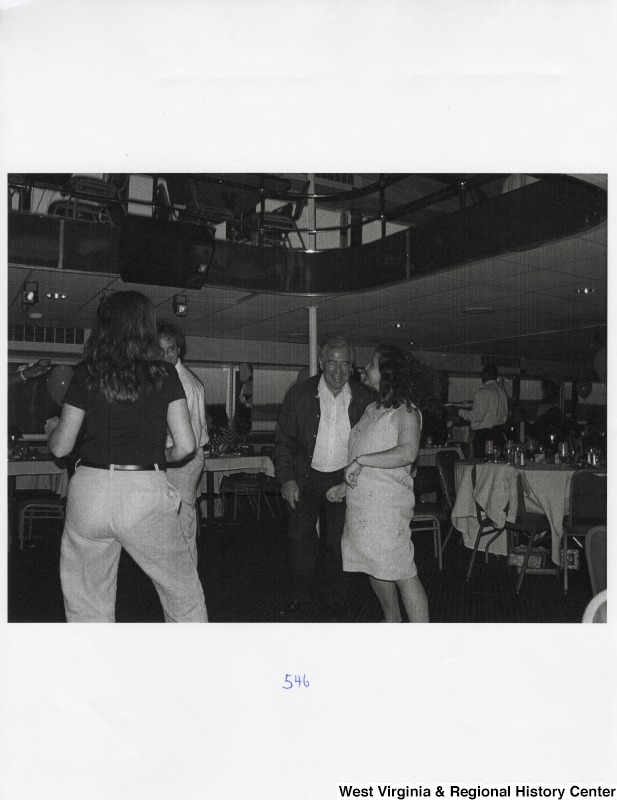 Several unidentified people dancing together on a dance floor at a party.
