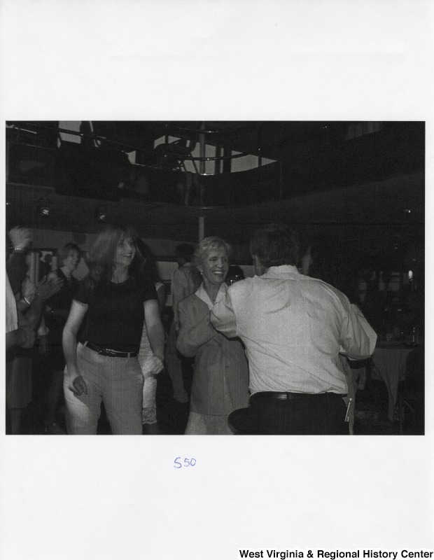 A group of unidentified people dance together on a dance floor at a party.