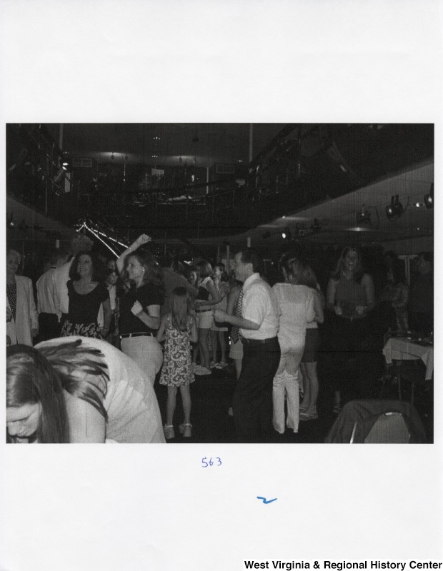 A large crowd of unidentified people dance together at a party.
