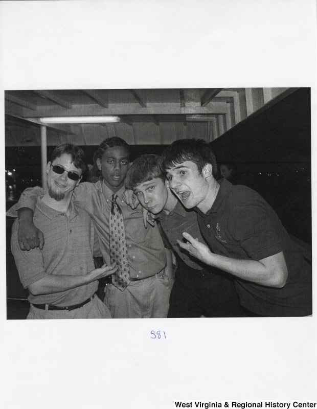 Four unidentified young men stand together for a photograph at a party.