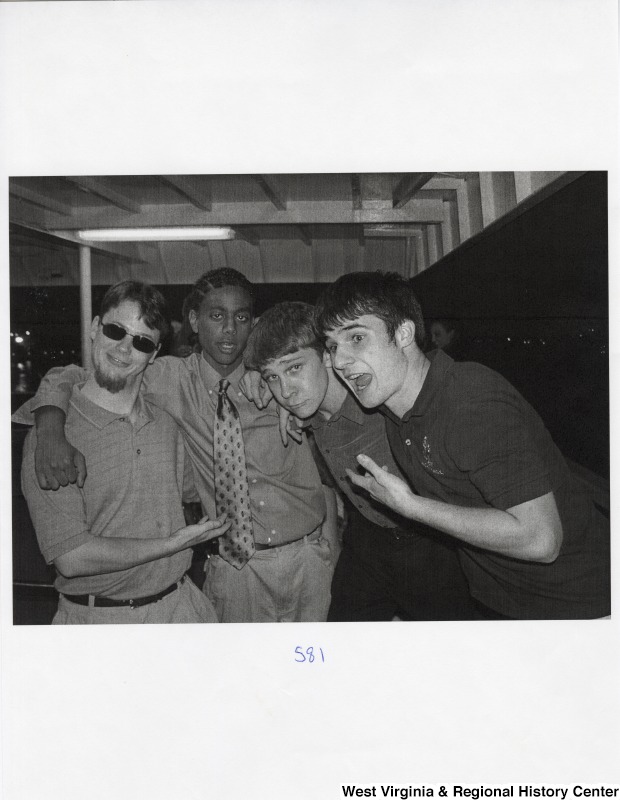 Four unidentified young men stand together for a photograph at a party.