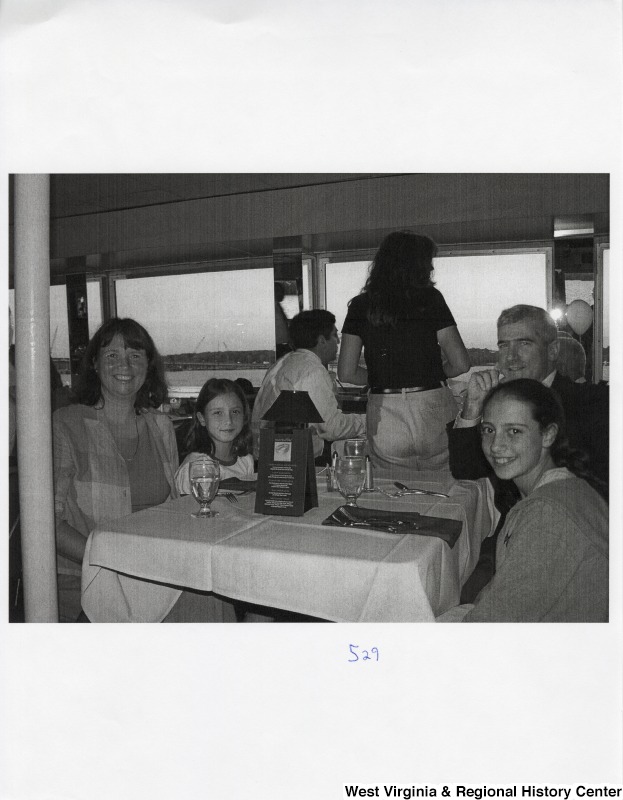 Four unidentified people sit around a dinner table in a public place.