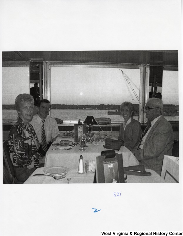 Four unidentified people sit around a table in a public place.