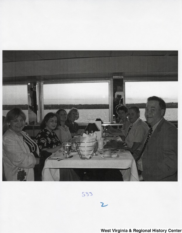 Eight unidentified people sit around a dinner table in a public place.