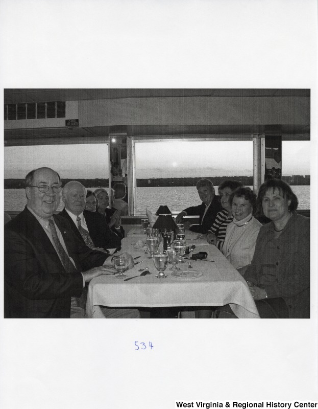 Eight unidentified people sit around a dinner table in a public place.