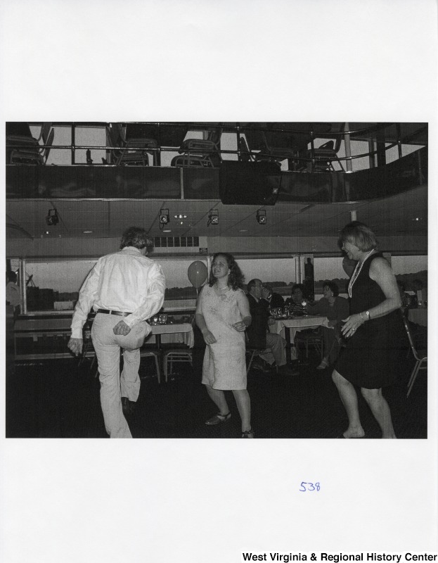 Three unidentified people dance at a party.