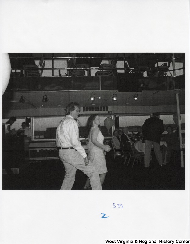 An unidentified man and an unidentified woman dance on a dance floor at a party.