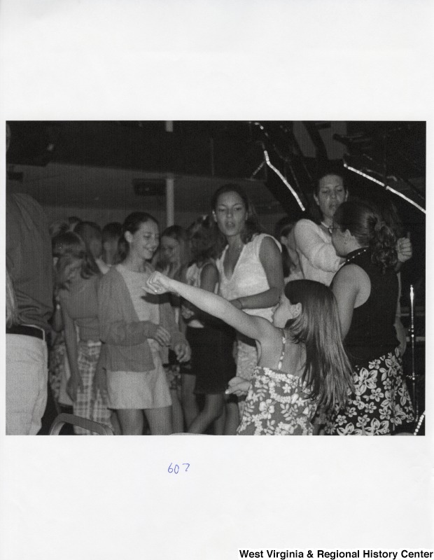 A large group of unidentified people dance together on a dance floor at a party.