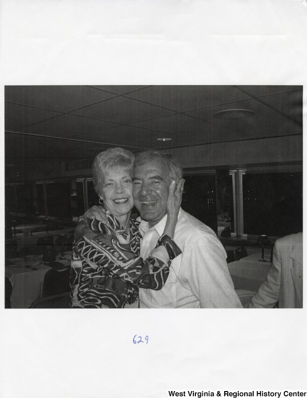 On the right, Representative Nick J. Rahall (D-W.Va.) smiles for a photograph with an unidentified woman at a party.