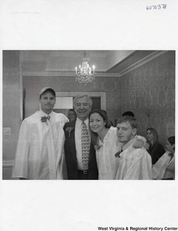 L-R: unidentified young man, Representative Nick J. Rahall (D-W.Va.), Suzanne Rahall, unidentified young manThese four smile for a picture with the young people in graduation gowns.