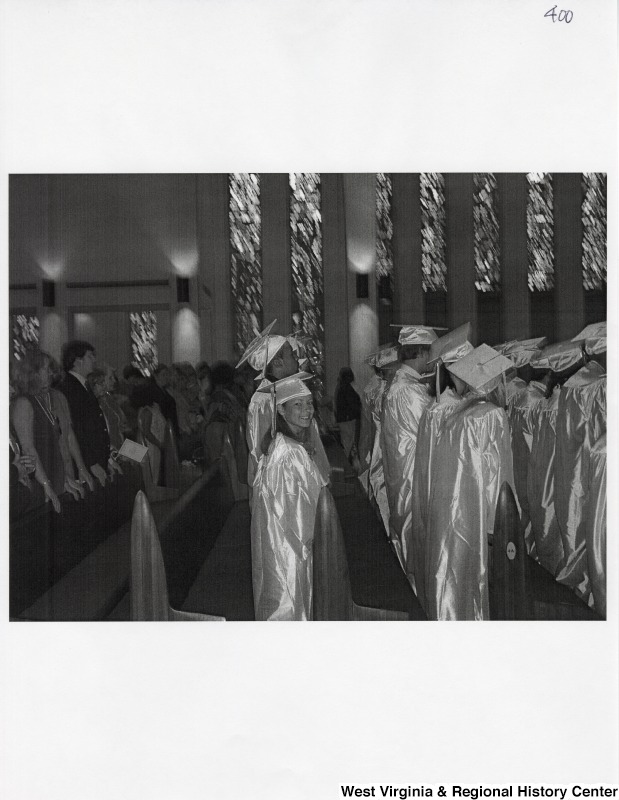 Suzanne Rahall looks at the camera from the aisle as she wears her graduation regalia at her commencement ceremony.