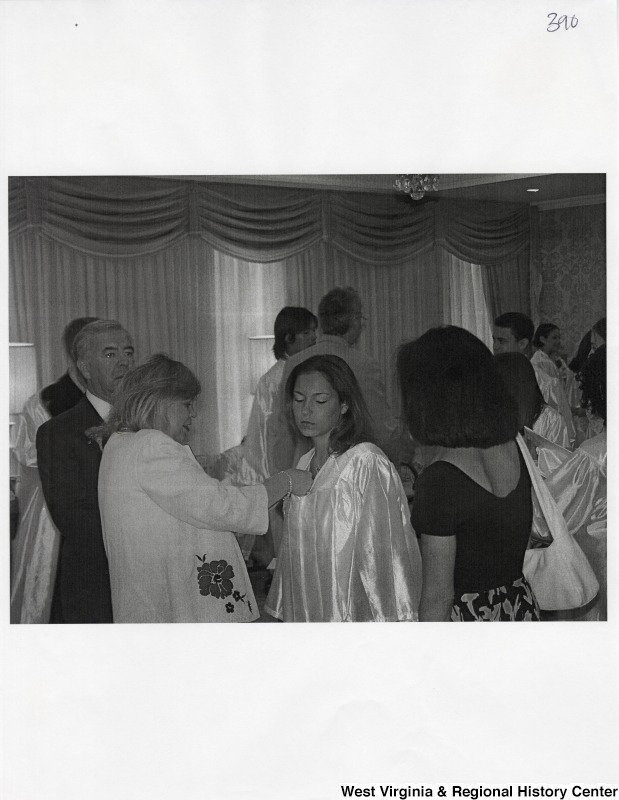 An unidentified woman adjusts a flower on Suzanne Rahall's graduation gown while Representative Nick J. Rahall (D-W.Va.) stands in the background.