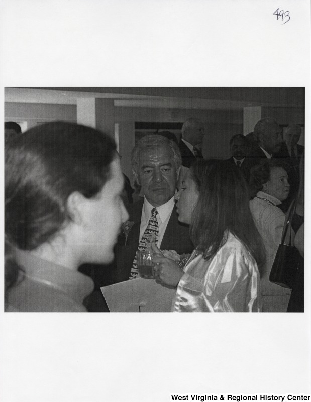 Representative Nick J. Rahall (D-W.Va.) and Suzanne Rahall stand talking to a group of unidentified people at a party.