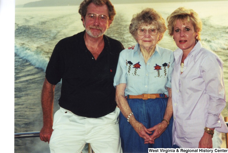 An unidentified man and two unidentified women stand for a photograph on a boat.