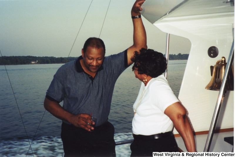 An unidentified man and an unidentified woman stand and talk on a boat.