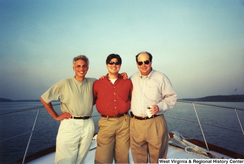 Three unidentified men stand for a photograph on a boat.