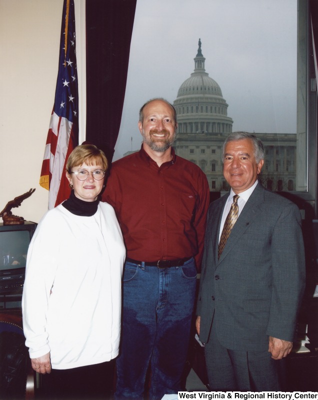 Representative Nick J. Rahall (D-W.Va.) stands between an unidentified man and woman in his office.