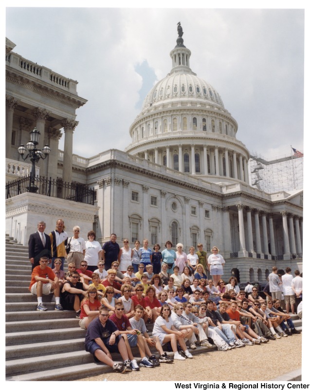 On the far left, Representative Nick J. Rahall (D-W.Va.) stands with an unidentified group of school students in front of the Capitol building.