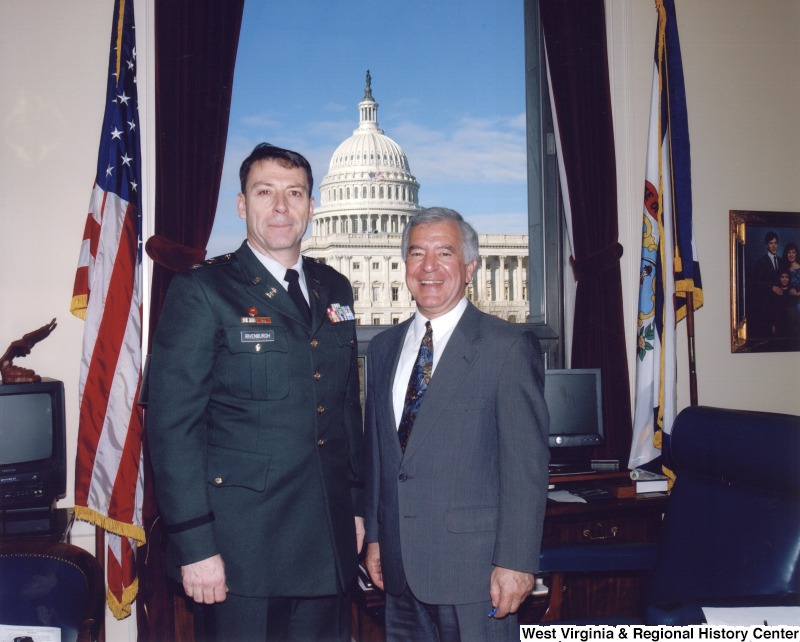 Representative Nick J. Rahall (D-W.Va.) stands for a photograph with a man named Rivenburgh in a military uniform in his office.