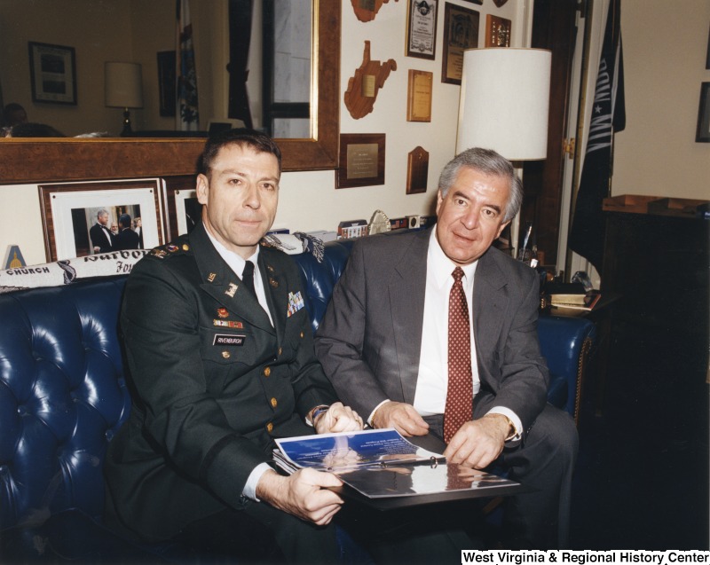 On the right, Representative Nick J. Rahall (D-W.Va.) sits with a man named Rivenburgh who is in a military uniform.