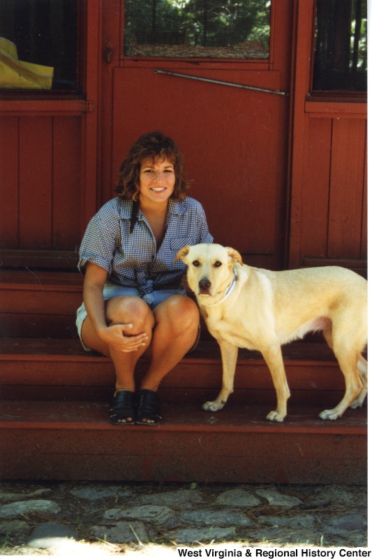 An unidentified woman sitting on a porch with a dog.
