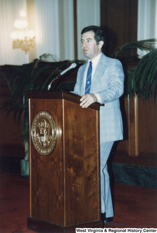 Representative Nick J. Rahall (D-W.Va.) stands behind a podium with a microphone.