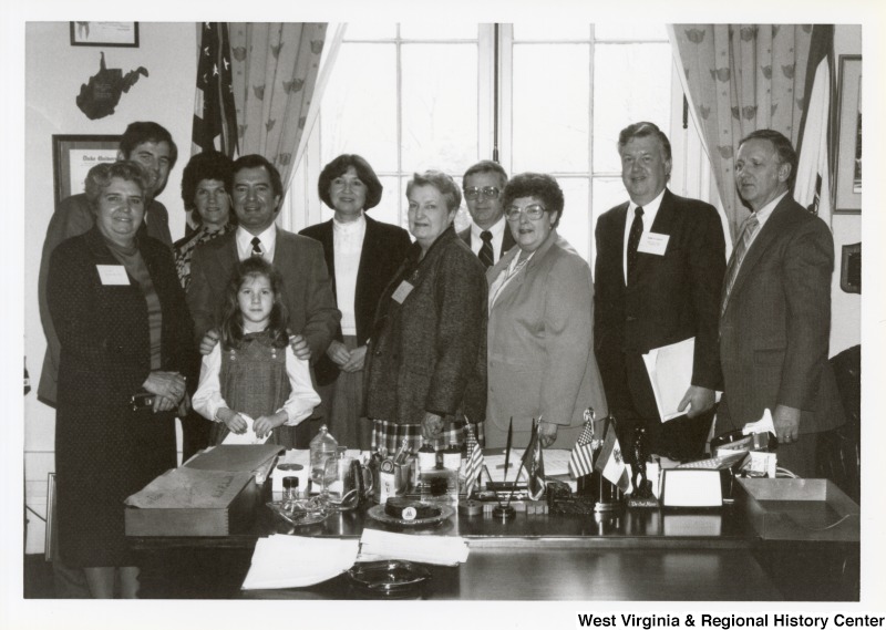 Representative Nick J. Rahall (D-W.Va.) stands in the center of a group of ten unidentified people.