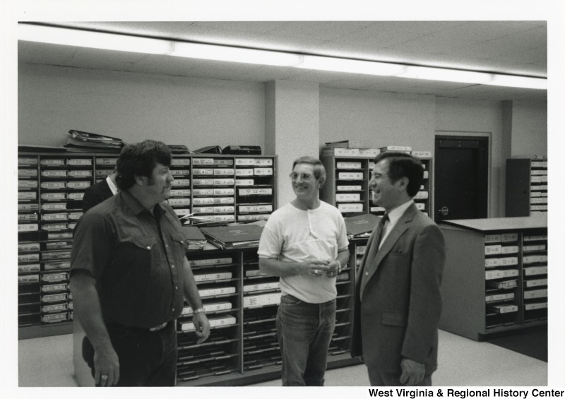 On the right, Representative Nick J. Rahall (D-W.Va.) talks with three unidentified men in a record room.