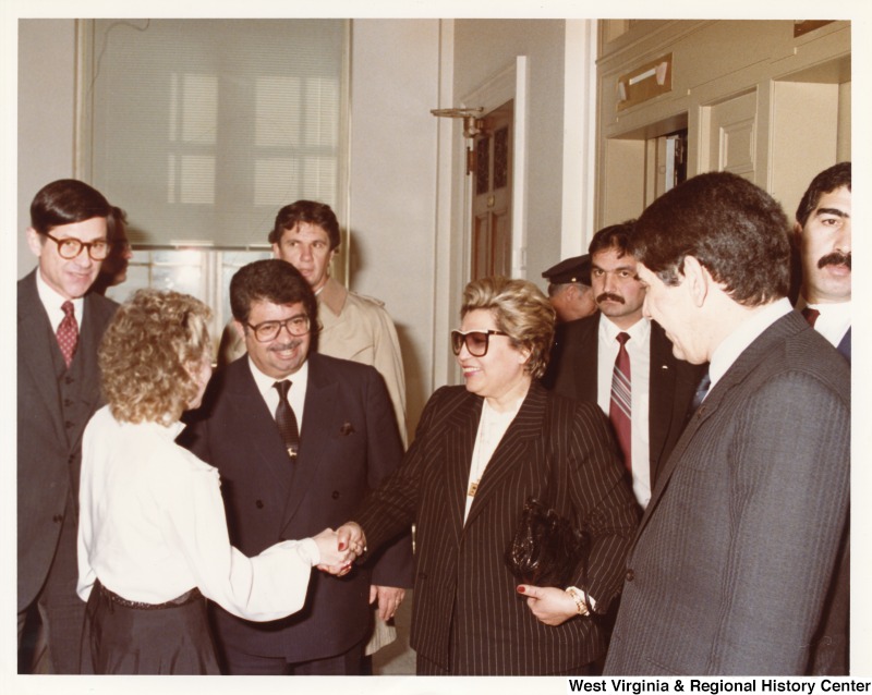 Third from the right stands Turgut zal, Prime Minister of Turkey, in a crowd of unidentified people.