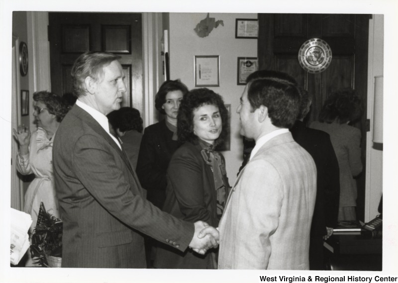 On the right, Representative Nick J. Rahall (D-W.Va.) shakes hands with an unidentified man in a crowd.