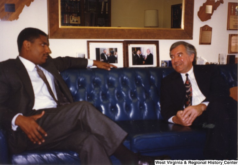 Representative Nick J. Rahall (D-W.Va.) (right) talking to Rodney Slater while seated on a couch.