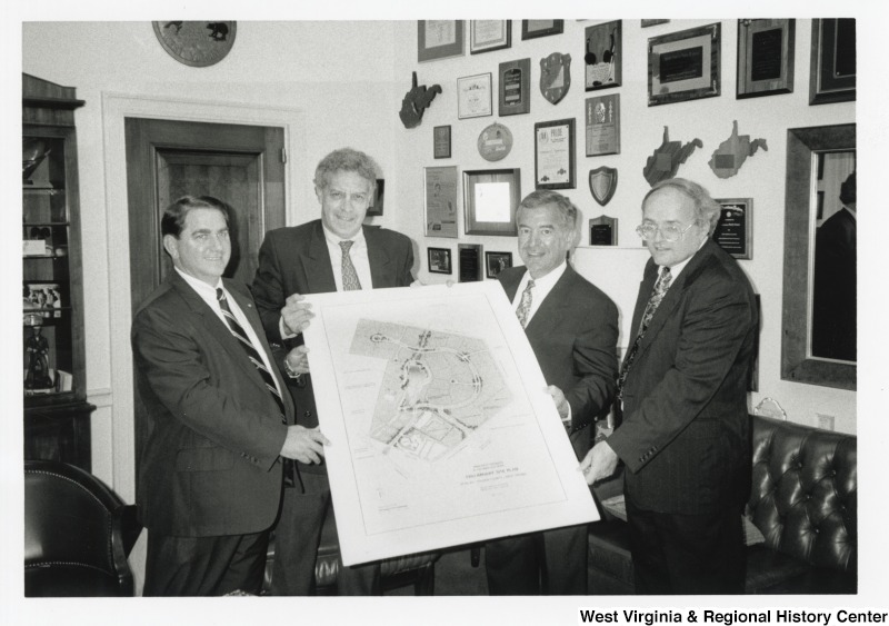 Second from the right, Representative Nick J. Rahall (D-W.Va.) stands with three unidentified men holding a preliminary site plan.